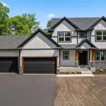 White siding house with triple black doors